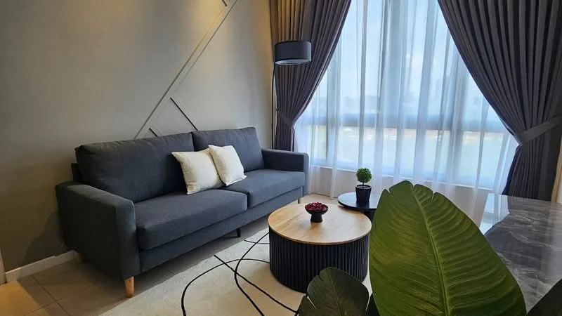 Living features: grey fabric 3-seater sofa, two decorative cushions, round coffee table with black base, decorative bowl with flowers on table, area rug with geometric pattern, floor-to-ceiling windows, sheer curtains, dark grey curtain drapes, potted plant, wall with geometric design; style: modern.