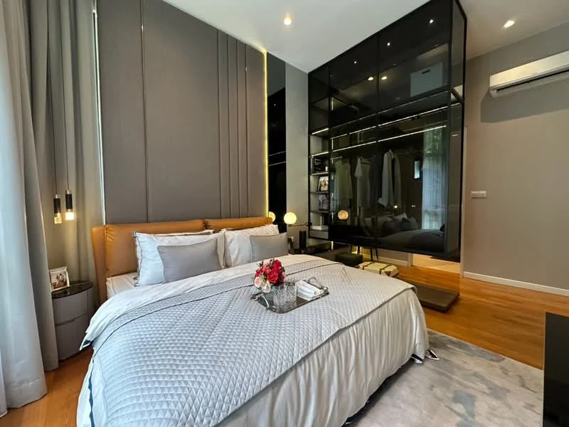Bedroom features: king-size bed with upholstered headboard, grey quilted bedspread, decorative pillows, nightstands with table lamps, built-in wardrobe with glass doors, wooden flooring, floor-to-ceiling curtains, recessed ceiling lights, air conditioning unit, decorative flower arrangement, area rug with soft texture; style: modern.
