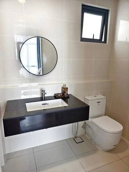 Bathroom features: black countertop with integrated sink, round mirror, chrome faucet, white one-piece toilet, wall-mounted toilet paper holder, grey tiled walls, light grey floor tiles, window for natural light; style: modern.