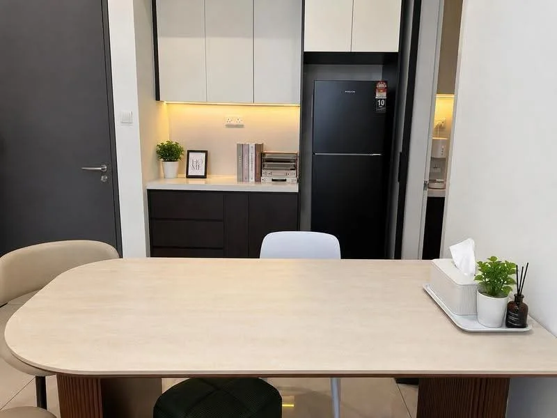 Dining features: round dining table with light wood finish, 4 dining chairs in cream and green upholstery, white ceramic vase with small plant, tissue box on tray, built-in cabinetry with dark wood finish, white upper cabinets, black refrigerator, ambient lighting under cabinets, cream tiled flooring; style: modern.