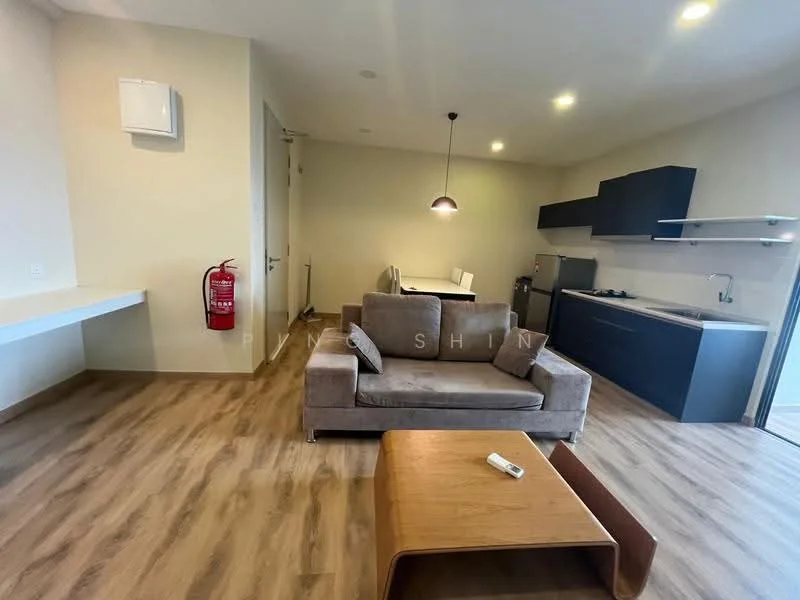 Living features: 3-seater fabric sofa in grey, wooden coffee table, wall-mounted air conditioning unit, laminate flooring, recessed downlights, open layout, dining table with chairs, kitchenette with dark cabinetry, stainless-steel fridge, built-in stove, sink, countertop with backsplash; style: modern.
