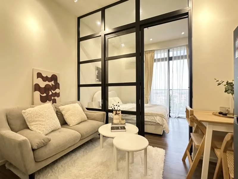 Living features: 3-seater fabric sofa in light grey, white area rug, round coffee table, 2 small round side tables, floor-to-ceiling windows, sheer curtains, wooden flooring, recessed downlights, decorative artwork on wall, open layout to bedroom area; style: modern; view: city. Bedroom features: queen-size bed with white bedding, glass partition wall, nightstand, bedside lamp, wall-mounted air conditioning unit; style: modern; view: city.