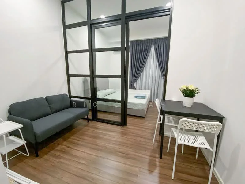 Living features: grey fabric sofa, wooden flooring, glass partition wall, dining table with white chairs, curtains in grey, air conditioning unit, decorative plant in ceramic pot, wall-mounted light fixture; style: modern. Room features: bed visible through glass partition, white bedding.