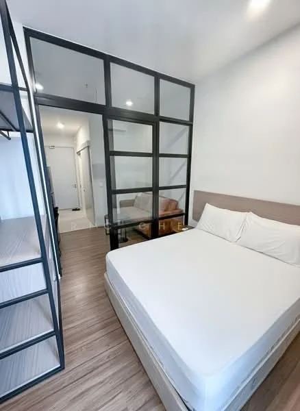 Bedroom features: queen-size bed with white bedding, wooden flooring, black metal frame partition, built-in shelving unit, white painted walls, recessed downlights, floor-to-ceiling glass partition, doorway leading to bathroom, minimalist decor; style: modern.