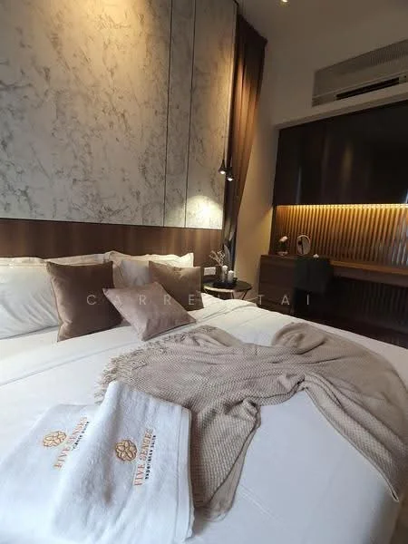 Bedroom features: king-size bed, upholstered headboard, white bedding, decorative throw pillows, beige throw blanket, wooden bedside table, table lamp, wall-mounted air conditioning unit, accent wall with marble finish, wood paneling, recessed lighting, decorative vase, framed artwork; style: modern.
