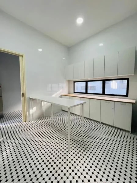 Kitchen features: white painted walls, black and white patterned tile flooring, flat-panel white cabinets, wood countertop, large window, recessed ceiling lights, open layout, minimalist design; style: modern.