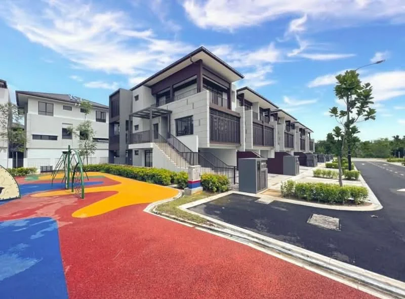 Exterior type: linked terrace house; features: grey and white painted facade, two-storey building, staircase leading to upper units, manicured landscaping, children's playground with rubber flooring, colorful play area with red and yellow surfaces, paved driveway, surrounding greenery, street view with no visible traffic, modern architectural design; style: modern.