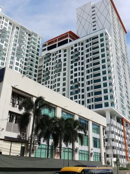 Exterior type: high-rise condominium; features: glass curtain wall, white painted facade, red accent elements, balconies with glass railings, multiple air conditioning units visible, manicured landscaping in front, modern architectural design, approximately 20-storey high-rise; style: modern.