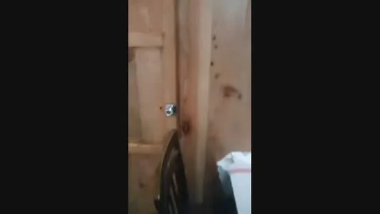 Room features: wooden door, wooden wall, metal doorknob, dark wooden chair, paper on surface.