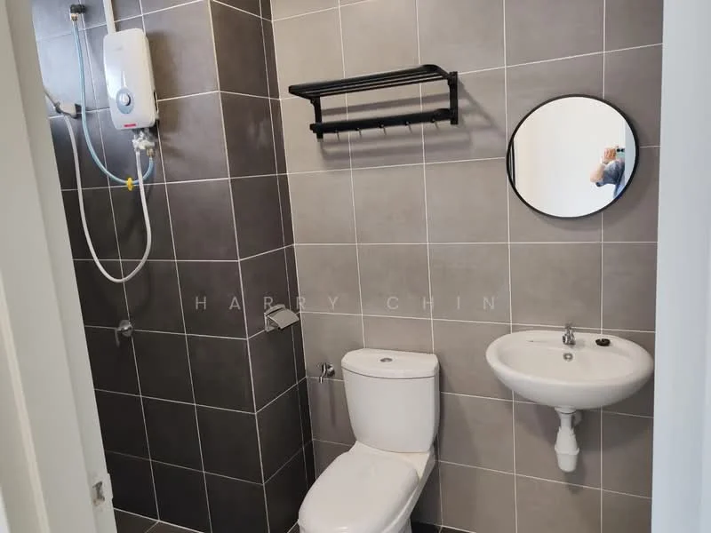 Bathroom features: grey tiled walls, white pedestal sink, chrome faucet, one-piece toilet, mirror with round frame, black wall-mounted shelf, water heater, shower area with tiled wall; style: modern.