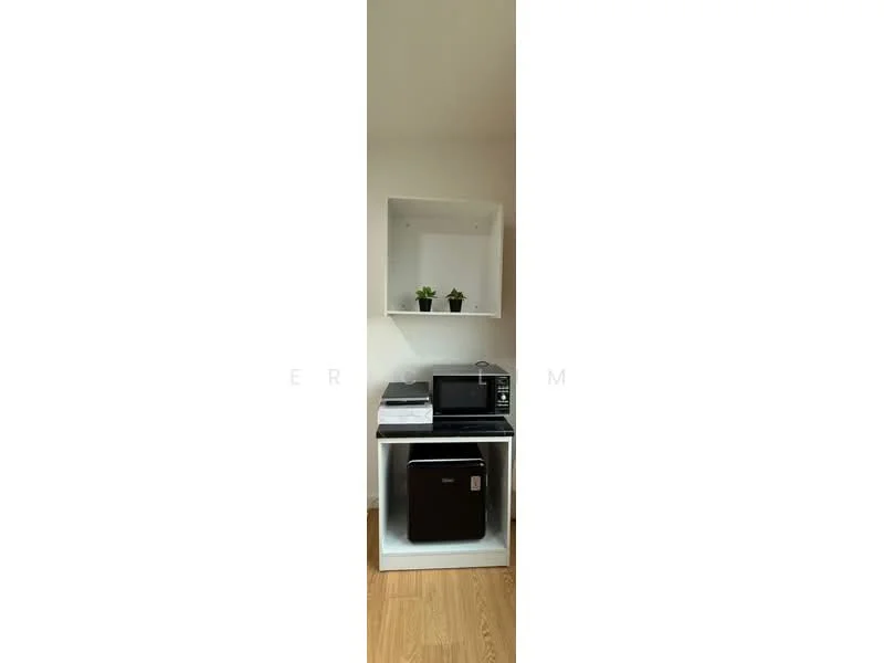 Room features: white shelving unit, black countertop, microwave, black fridge, two potted plants, wooden flooring; style: modern.