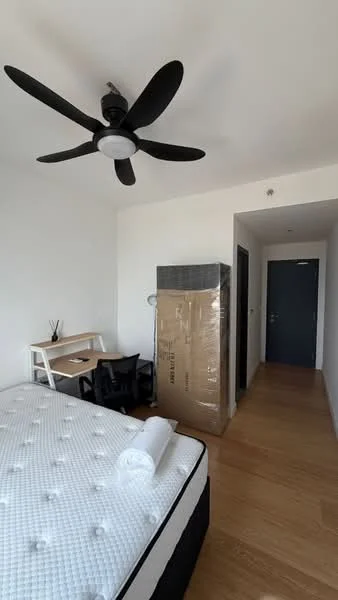 Bedroom features: queen-size bed with mattress, 5-blade ceiling fan with light, wooden flooring, white painted walls, desk with chair, large cardboard box, doorway leading to hallway, window with natural light; style: modern.