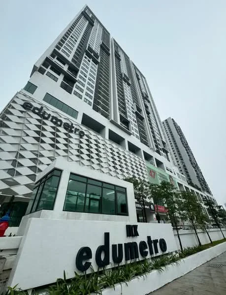 Exterior type: high-rise condominium; features: glass curtain wall, white painted facade, geometric pattern on facade, multiple storeys, landscaped area with plants, prominent signage, modern architectural design; style: modern.