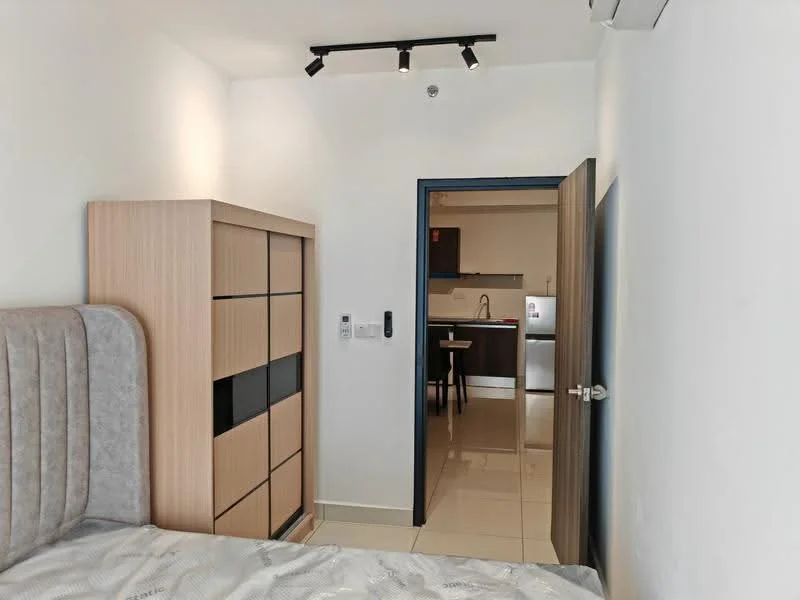 Room features: light-colored walls, glossy tile flooring, built-in wardrobe with sliding doors, bed with upholstered headboard, track lighting, door leading to kitchen area, air conditioning unit, open doorway, kitchen visible in background; style: modern.