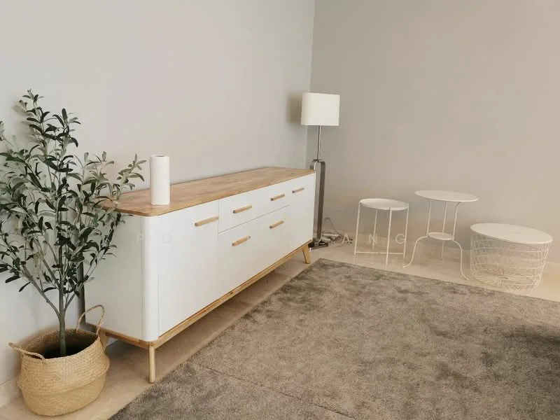Room features: white sideboard with wooden top, metal floor lamp, small round white side table, wireframe side table, decorative plant in woven basket, light grey area rug, plain grey painted walls, neutral flooring; style: modern.