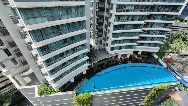 Exterior type: high-rise condominium; features: glass curtain wall, recessed balconies, infinity pool, pool deck with loungers, landscaped garden area, outdoor seating area, surrounded by mature greenery, modern architectural design; style: modern.