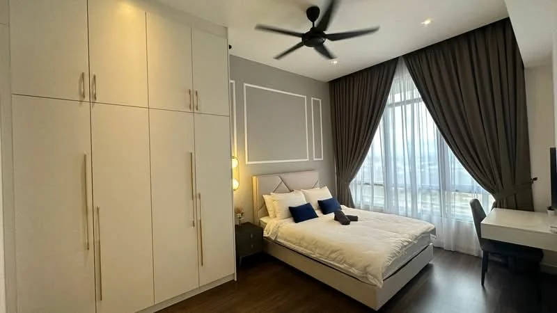 Bedroom features: queen-size bed with white bedding, upholstered headboard, two blue decorative pillows, built-in wardrobe with white finish, wooden flooring, floor-to-ceiling windows with sheer curtains, 5-blade ceiling fan, study desk with chair, wall-mounted TV, decorative wall paneling, grey accent wall; style: modern; view: city.
