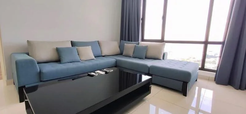 Living features: L-shape sectional sofa in blue, decorative cushions in light grey and blue, black coffee table, floor-to-ceiling windows, curtains in dark blue, glossy tile flooring, city view, wall-mounted TV, remote controls on coffee table; style: modern; view: city.