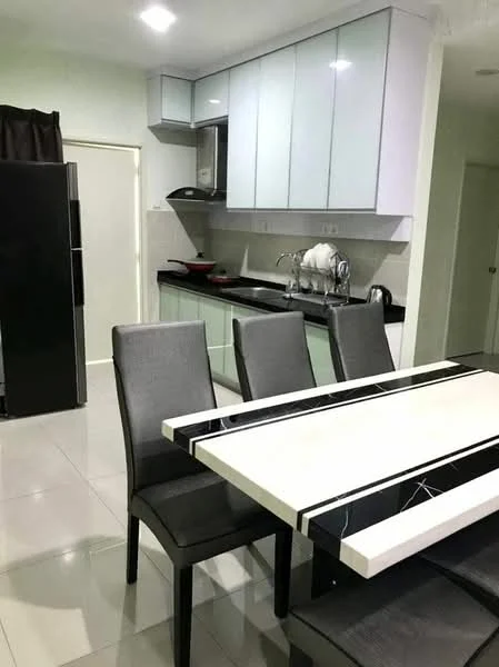 Kitchen features: light grey cabinetry with glossy finish, black countertop, stainless-steel sink, chrome pull-down faucet, built-in oven, stainless-steel range hood, ceramic tile flooring, refrigerator, dining table with black and white design, four black dining chairs, wall-mounted cabinets, kitchen utensils on countertop; style: modern.