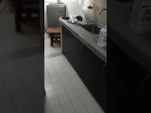 Kitchen features: single-bowl stainless-steel sink, chrome pull-down faucet, dark cabinetry, white tiled backsplash, ceramic tile flooring, countertop with grey finish, built-in washing machine, wooden stool, kitchen utensils on countertop, window with sheer curtains; style: modern.