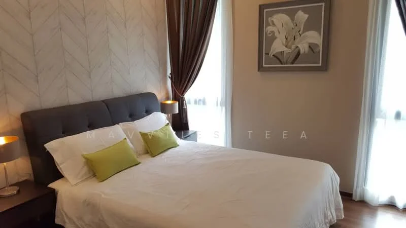 Bedroom features: king-size bed with upholstered headboard, white bedding, two green accent pillows, wooden bedside table, table lamp with grey shade, framed artwork on wall, light brown wooden flooring, curtains in dark brown, floor-to-ceiling windows, wall with herringbone pattern; style: modern.