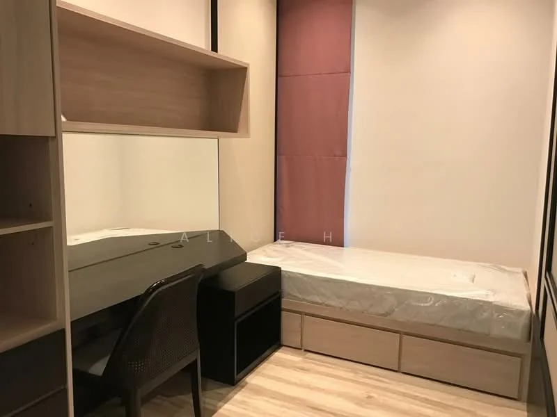 Bedroom features: single bed with mattress, built-in wardrobe, study desk with mirror, black storage unit, wooden flooring, light-colored walls, curtains, shelf above desk; style: modern.