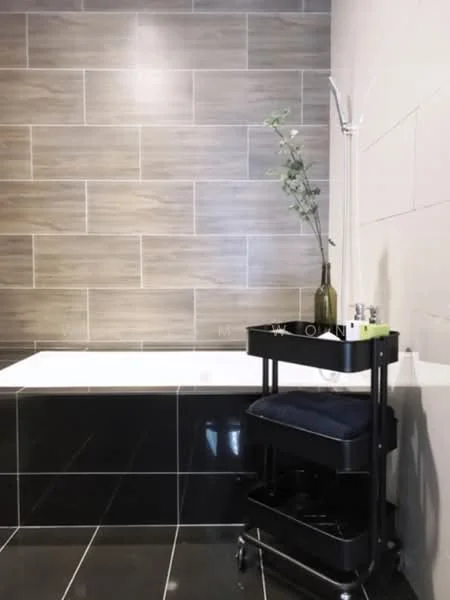 Bathroom features: freestanding bathtub, black tiled flooring, grey wall tiles, wooden accent wall, shower with handheld shower head, towel rack, decorative plant in vase, rolling cart with toiletries; style: modern.