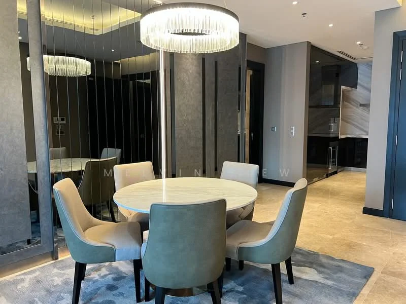 Dining features: round dining table, upholstered dining chairs in grey, chandelier with crystal accents, mirrored wall, neutral wall colour, marble flooring, area rug with geometric pattern, recessed lighting; style: modern. Kitchen features: modern cabinetry, stainless-steel appliances, marble countertop, open layout; style: modern.
