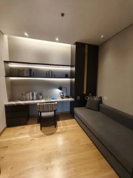 Study features: wooden flooring, grey fabric sofa, built-in shelving with backlighting, desk with drawers, desk lamp, decorative books, wall-mounted lighting, neutral painted walls; style: modern.