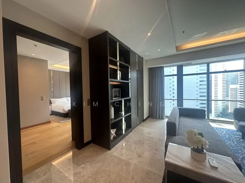 Living features: floor-to-ceiling windows, grey fabric sofa, marble flooring, wooden shelving unit, recessed downlights, decorative plant on coffee table, area rug with geometric pattern, city view, open layout to adjacent room; style: modern; view: city. Room features: wooden door, light wood flooring, neutral painted walls, recessed lighting.