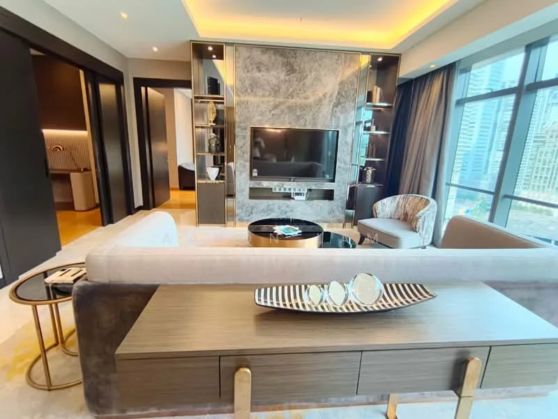Living features: grey fabric sofa, round coffee table with black top, gold accent side table, wall-mounted TV, marble feature wall, built-in shelving units, floor-to-ceiling windows, city view, recessed lighting, decorative bowl on table, upholstered accent chair, area rug with abstract pattern; style: modern; view: city.