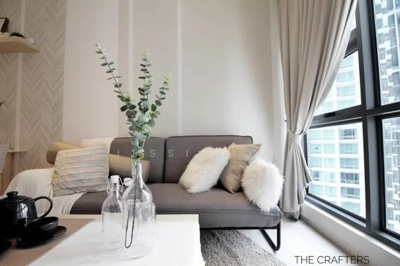 Living features: grey fabric sofa, white throw pillows, decorative vase with greenery, glass coffee table, white tablecloth, floor-to-ceiling windows, sheer curtains, wooden shelving unit, textured accent wall, light-colored walls, neutral-toned area rug; style: modern; view: city.