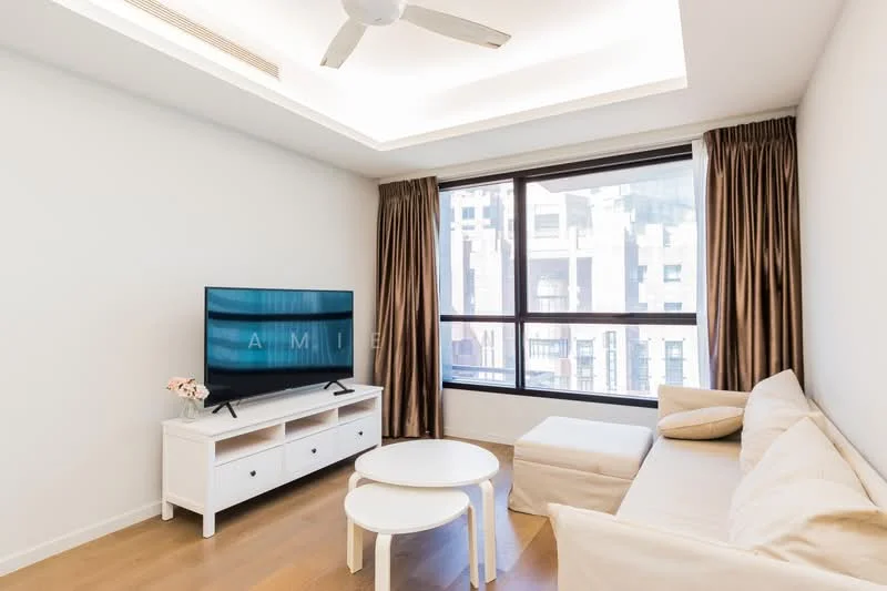 Living features: light wood flooring, white painted walls, tray ceiling with recessed lighting, floor-to-ceiling windows, brown curtains, 3-seater beige fabric sofa, white coffee table, TV console in white, wall-mounted TV, decorative plant on console; style: modern; view: city.