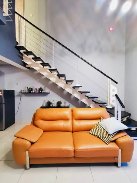 Living features: orange leather sofa, decorative throw pillow, open shelving with plants, stainless-steel fridge, white tiled flooring, grey painted walls, staircase with black steps and white railing, recessed ceiling lights; style: modern.