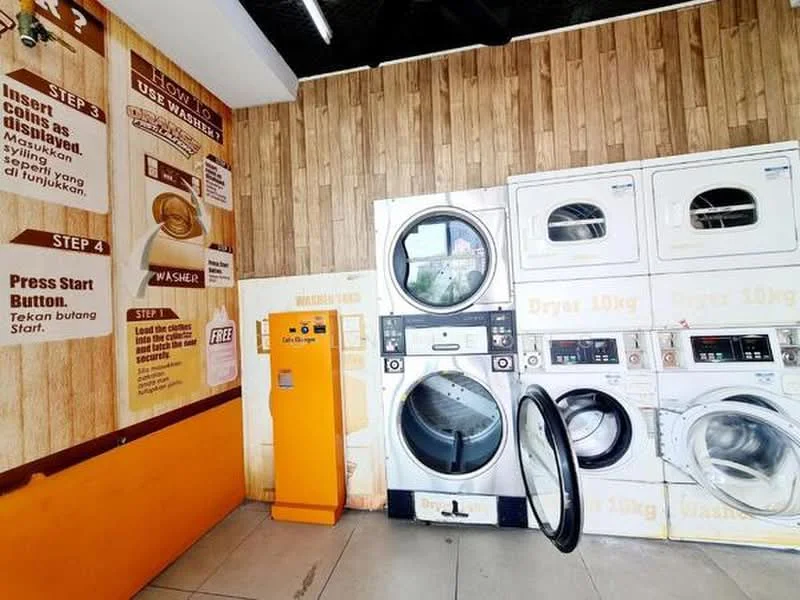 Laundry features: front-load washing machine, front-load dryer, coin-operated washer, coin-operated dryer, orange vending machine, wood paneling on walls, tile flooring, instructional signage on walls; style: modern.