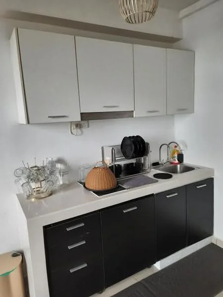 Kitchen features: white upper cabinets, black lower cabinets, marble countertop, single-bowl stainless-steel sink, chrome pull-down faucet, built-in stove, dish rack, kitchen utensils, decorative bowl, glassware, wall-mounted cabinet, recessed lighting; style: modern.