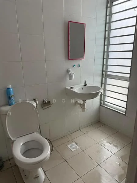 Bathroom features: white tiled walls, cream tiled flooring, single-sink wall-mounted basin, chrome basin mixer faucet, one-piece toilet, framed mirror, window with horizontal slats, toilet paper holder, cleaning bottle, drainage grate on floor.