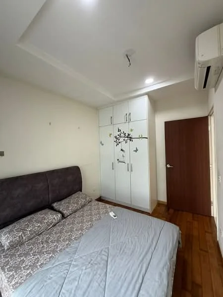 Bedroom features: queen-size bed with grey upholstered headboard, bedding with floral pattern, wooden flooring, built-in wardrobe with white finish and floral design, recessed ceiling lights, wall-mounted air conditioning unit, plain white walls, door with wooden finish; style: modern.