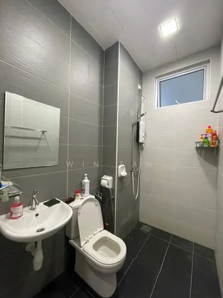 Bathroom features: grey tiled walls, black tiled flooring, single-sink vanity, chrome basin mixer faucet, wall-mounted mirror, one-piece toilet, handheld shower, shower head, shower curtain rod, shelf with toiletries, window for natural light, light fixture on ceiling; style: modern.