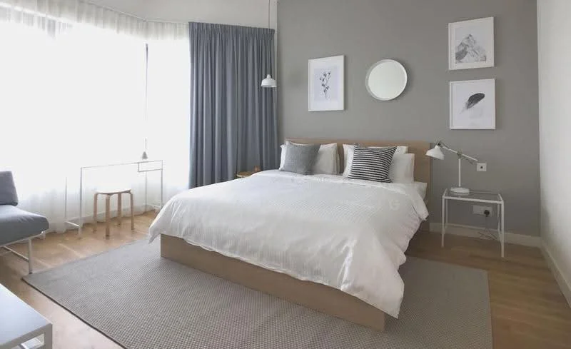 Bedroom features: king-size bed with white bedding, upholstered headboard, two bedside lamps, framed artwork on walls, light grey accent wall, floor-to-ceiling windows with sheer curtains, wooden flooring, area rug with neutral color, small desk with clear glass top, stool, pendant light, mirror on wall; style: modern; view: city.