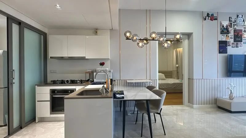 Kitchen features: white cabinetry, black countertop, stainless-steel gas stove, built-in oven, stainless-steel range hood, single-bowl stainless-steel sink, chrome pull-down faucet, pendant lighting, open-plan layout, marble tile flooring; style: modern. Living features: wall-mounted TV, sofa, decorative wall with photos, wood flooring, area rug, coffee table, recessed lighting; style: modern.