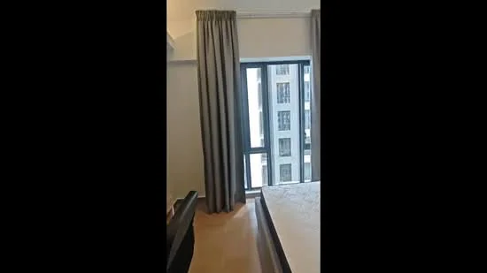 Bedroom features: floor-to-ceiling window, grey curtains, wooden flooring, queen-size bed, bedside table, desk with chair, decorative wall, light fixture; style: modern; view: city.