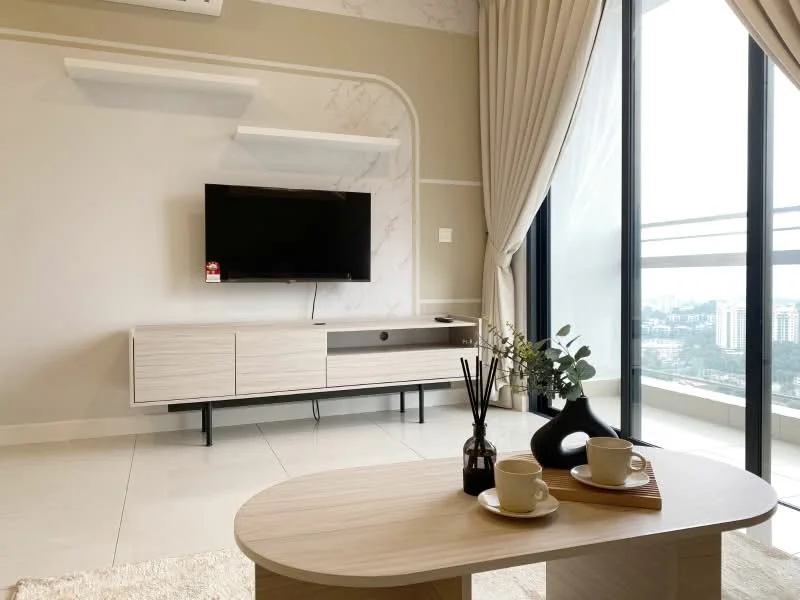 Living features: light-colored wall with marble accent, floor-to-ceiling windows, curtains in light fabric, light-colored tiled flooring, modern TV console in light wood, wall-mounted flat-screen TV, decorative vase, coffee table in light wood, two cups on saucers, decorative reed diffuser, minimalist decor, indoor plants; style: modern; view: city.