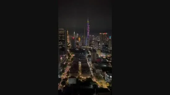Exterior type: high-rise condominium; features: city skyline view, night lighting, surrounded by urban landscape, visible high-rise buildings, street view with illuminated roads; style: modern.