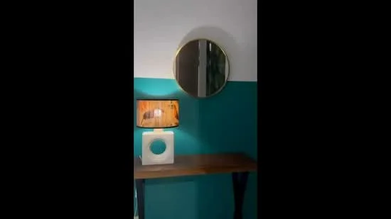 Room features: teal painted wall, white painted wall, round mirror with gold frame, wooden console table, table lamp with wooden base and white shade; style: modern.
