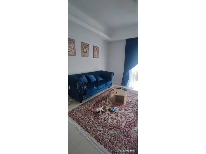 Living features: blue velvet sofa with studded detailing, three blue cushions, large area rug with intricate patterns, white walls, light-colored tiled flooring, floor-to-ceiling windows with sheer curtains, decorative wall art, coffee table, toys scattered on the floor; style: modern.