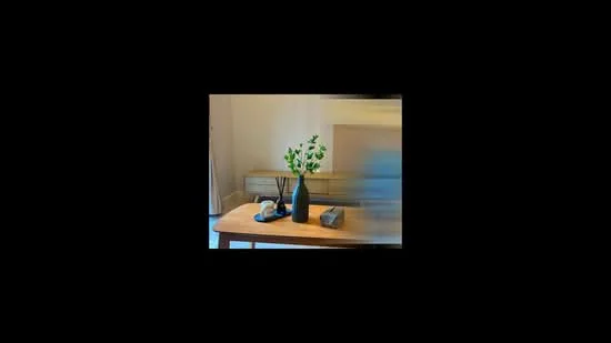 Room features: wooden coffee table, black vase with greenery, decorative stones, light-colored wall, neutral-colored sofa, shelf or console unit in the background; style: modern.