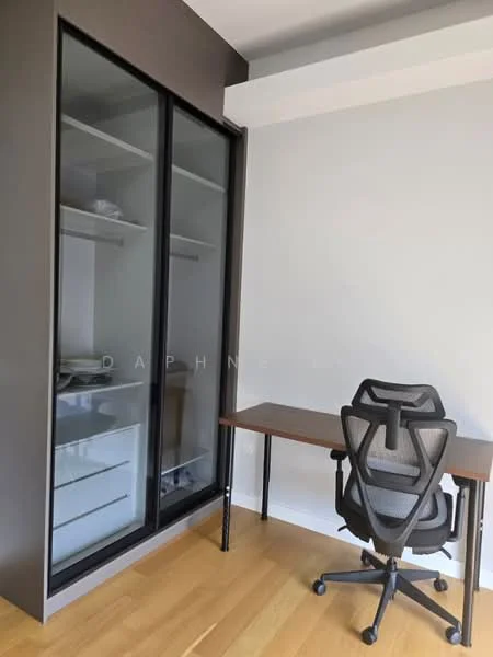Study features: wooden flooring, grey painted walls, glass-fronted storage cabinet, desk with metal legs, ergonomic office chair, built-in shelving, natural light from window, minimalist decor; style: modern.