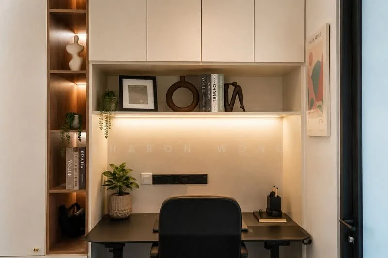 Study features: built-in desk with black surface, white cabinetry with upper storage, open shelving with decorative items, framed artwork on wall, LED strip lighting under shelves, green potted plant, black office chair, power outlet on wall, books on shelf, minimalist decor; style: modern.
