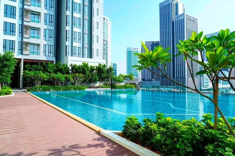 Exterior type: high-rise condominium; features: infinity pool, pool deck with loungers, landscaped garden with tropical plants, manicured lawn, surrounded by high-rise buildings, wooden decking, water features, city skyline in background; style: modern.